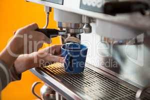 Female barista preparing coffee with machine in cafeteria