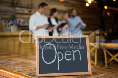 Open signboard with customers in background at coffee shop