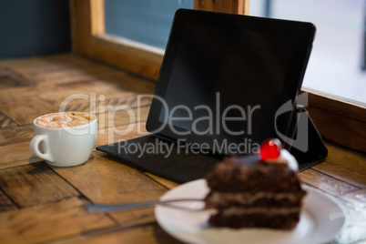 Digital tablet with pastry and coffee cup on table