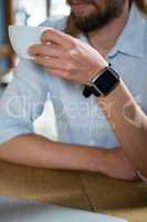 Man wearing smart watch while having coffee in cafe