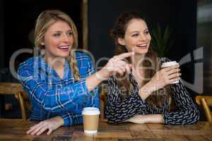 Smiling woman showing something to friend in coffee shop