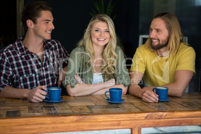 Happy woman with male friends at table in coffee shop