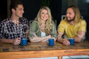 Happy woman with male friends at table in coffee shop