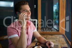 Young man talking on mobile phone in coffee shop