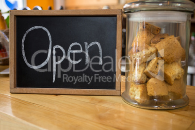 Open sign by cookies in jar on counter