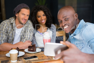 Friends taking selfie at wooden table in coffee shop