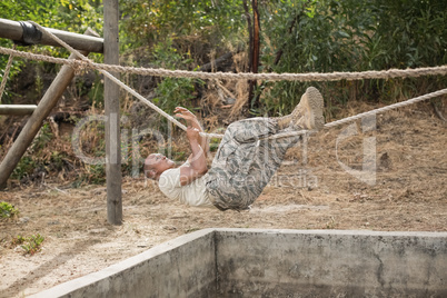 Military soldier climbing rope during obstacle course training