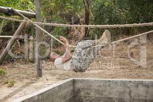 Military soldier climbing rope during obstacle course training