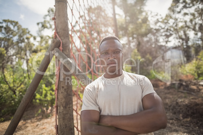 Military man standing with arms crossed during obstacle course