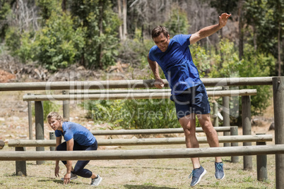 Man and woman jumping over the hurdles during obstacle course