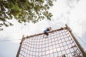 Fit woman climbing a net during obstacle course