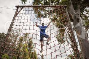 Fit man climbing a net during obstacle course