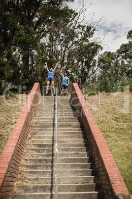 Happy fit man and woman standing near staircase during obstacle course