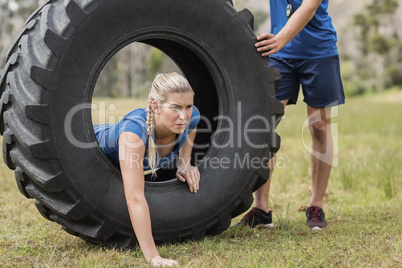 Woman crawling through the tire during obstacle course
