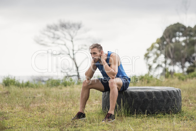 Tired fit man sitting on tire