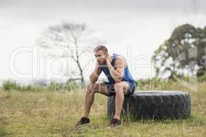 Tired fit man sitting on tire