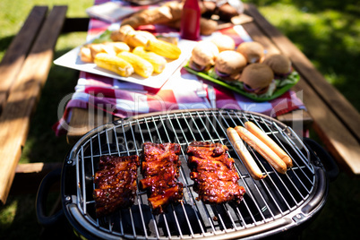 Barbeque with buns and corn on table in park