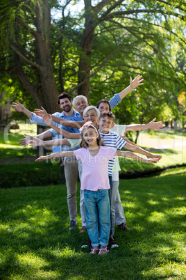 Multi generation family standing in a row with arms outstretched