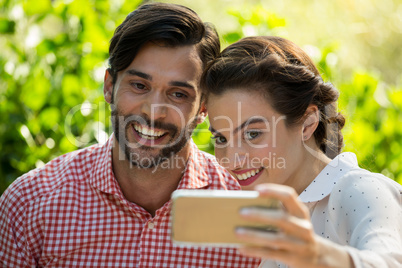 Cheerful couple taking slefie through smart phone at park