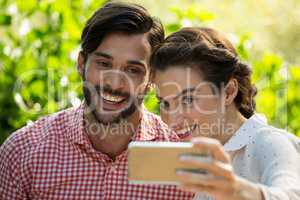 Cheerful couple taking slefie through smart phone at park