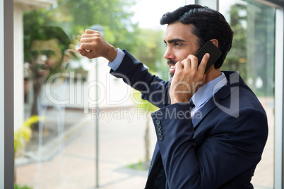 Businessman talking on mobile phone while looking through the window