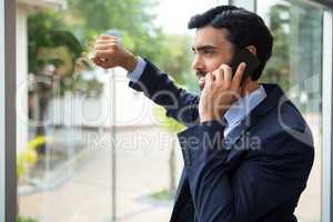 Businessman talking on mobile phone while looking through the window