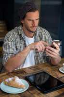 Handsome man using mobile phone at table in coffee shop