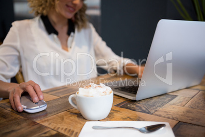Woman using laptop with coffee on table in cafe