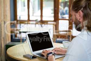 Side view of man using laptop in coffee shop