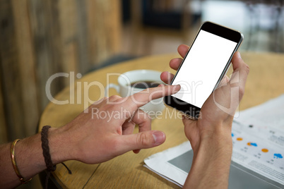 Man using mobile phone at table in cafeteria