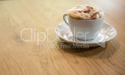 Coffee cup with creamy froth on table at cafe