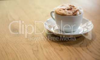 Coffee cup with creamy froth on table at cafe