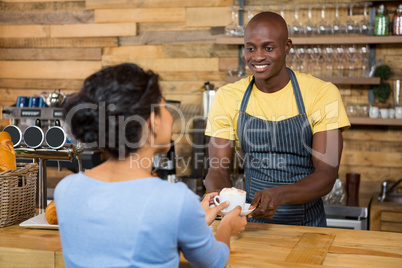 Male barista serving coffee to customer in coffee shop