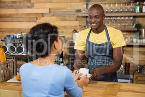 Male barista serving coffee to customer in coffee shop