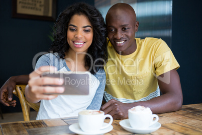 Couple taking selfie with cellphone in coffee shop