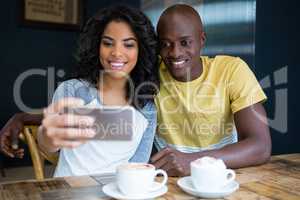 Couple taking selfie with cellphone in coffee shop