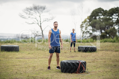 Fit woman standing near tyre during obstacle course
