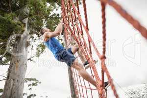 Man climbing a net during obstacle course
