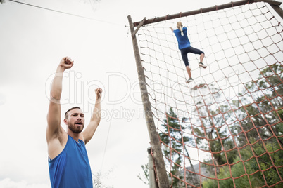 Woman climbing a net during obstacle course