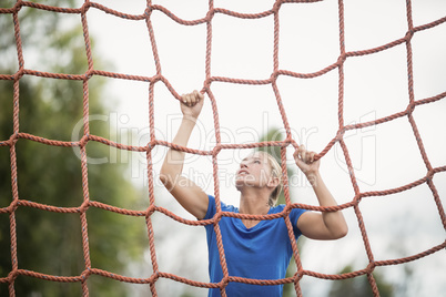 Woman climbing a net during obstacle course