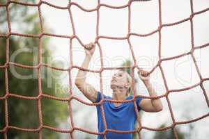 Woman climbing a net during obstacle course