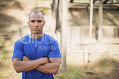 Portrait of fit man standing with arms crossed during obstacle course