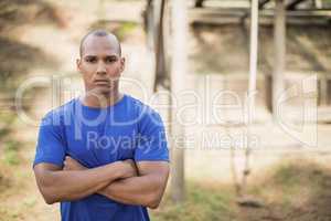 Portrait of fit man standing with arms crossed during obstacle course