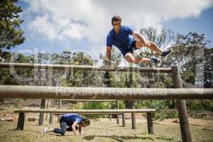 Man and woman jumping over the hurdles during obstacle course