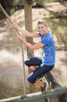 Smiling fit woman climbing down the rope during obstacle course