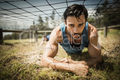 Fit man crawling under the net during obstacle course