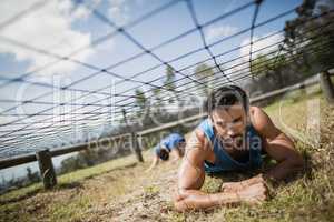 Fit man crawling under the net during obstacle course