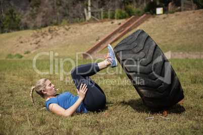 Fit woman performing leg workout with tier during obstacle course
