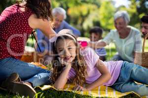 Girl resting on blanket besides family enjoying the picnic