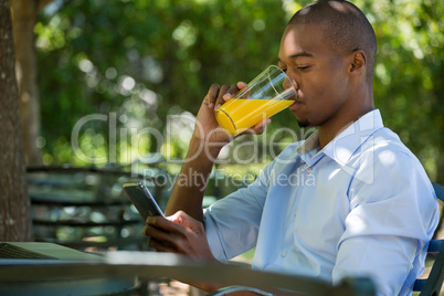 Man drinking juice while using mobile phone at restaurant